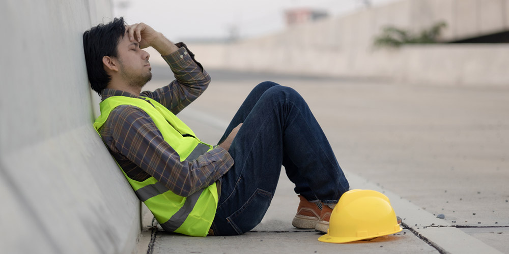 MedLife - trabajador con chaleco de seguridad y casco sentado en el suelo, reflejando la fatiga laboral que busca evitar la Ley Silla